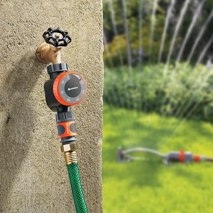 Gardena water timer on a faucet feeding a hose to a lawn sprinkler