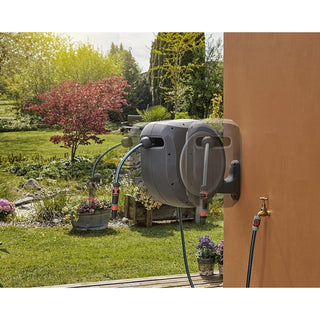 Gardena RollUp reel on a wall above a planted border
