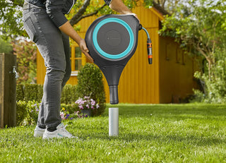 Gardener screwing the Gardena hose box spike into a lawn