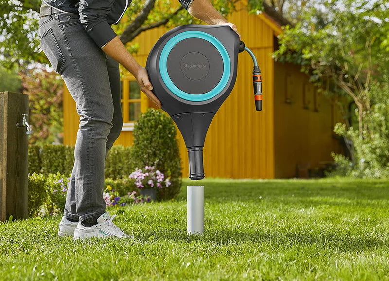 Gardener screwing the Gardena hose box spike into a lawn