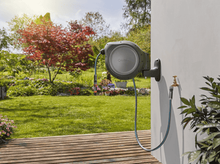 Gardena RollUp reel on a white wall above a wooden deck