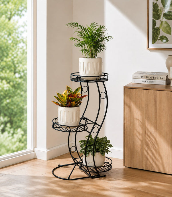 Cocoyard three tier metal plant stand holding three potted houseplants beside a window