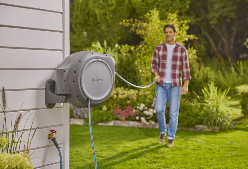 Gardener pulling hose out from the wall-mounted Gardena reel