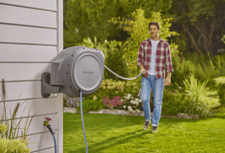 Gardener pulling hose out from the wall-mounted Gardena reel