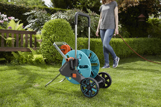 Gardener walking away from the Gardena hose trolley on a lawn
