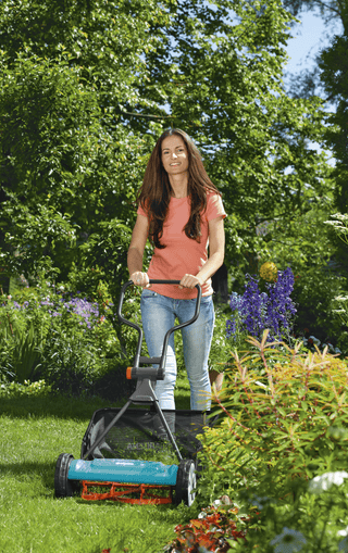 Woman mowing with a Gardena reel mower and the grass catcher between flower beds