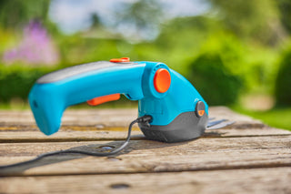 Gardena battery grass shears charging on a wooden garden table