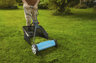 Man mowing a lawn with the grass catcher fitted to a Gardena reel mower