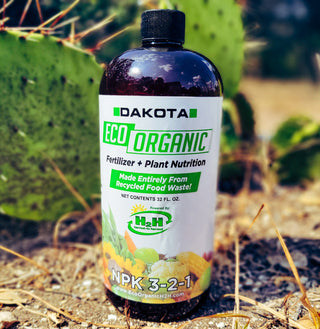 32 oz bottle of Dakota Eco liquid fertilizer, NPK 3-2-1, outdoors beside a cactus