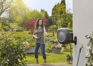 Gardener walking out with hose from the Gardena RollUp reel
