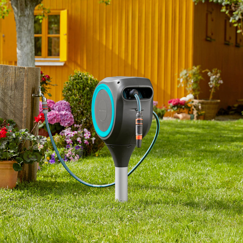 Gardena RollUp S hose box standing in a garden by a yellow house