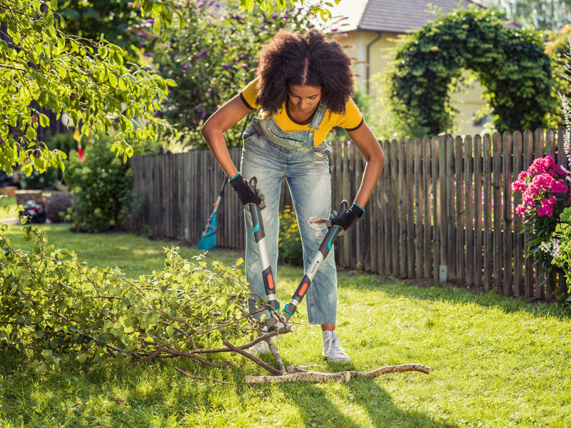 Gardener cutting fallen branches on a lawn with the Gardena TeleCut