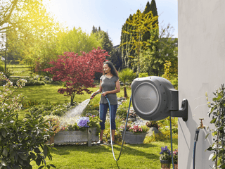 Gardener watering plants with hose from the Gardena RollUp reel