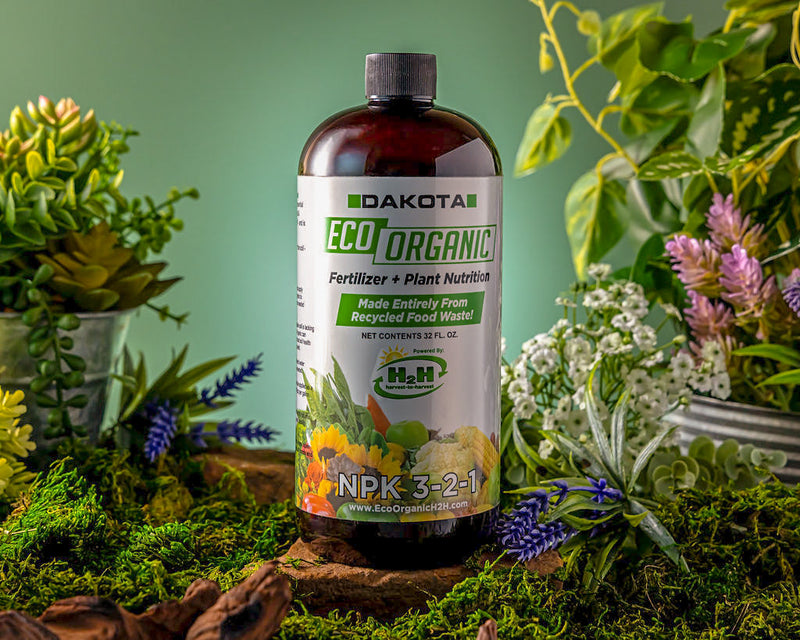 Dakota Eco 32 oz fertilizer bottle among potted flowering plants