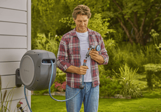 Gardener checking the spray nozzle next to the Gardena reel
