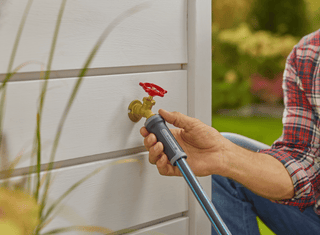 Hand connecting a hose to an outdoor faucet