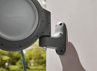 Hand fitting the Gardena RollUp reel onto its wall bracket
