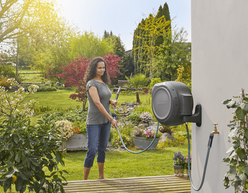 Gardener watering flower pots with hose from the Gardena RollUp reel