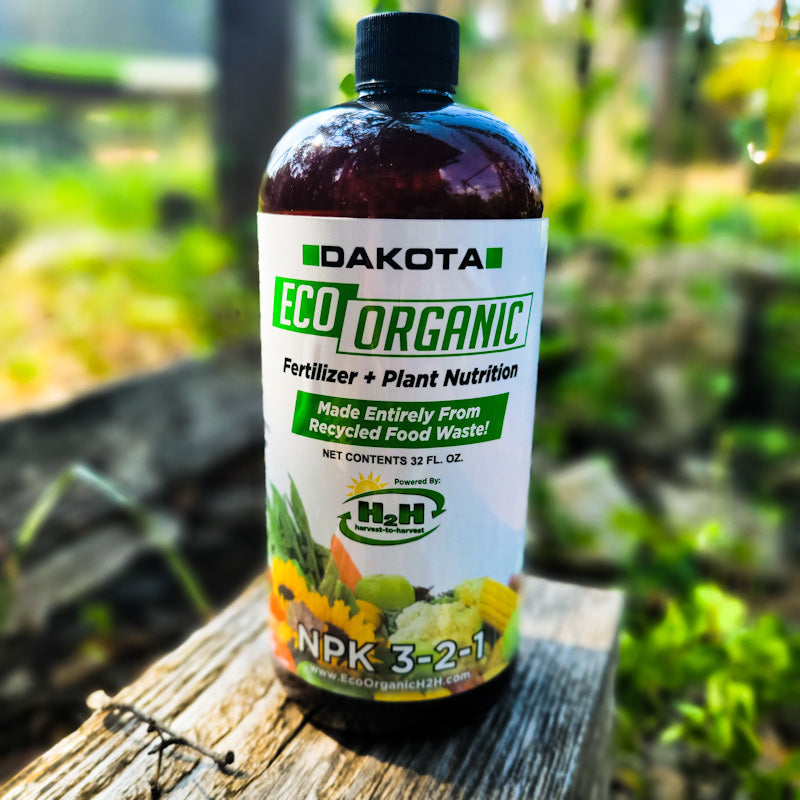 Dakota Eco 32 oz fertilizer bottle standing on a weathered board outdoors